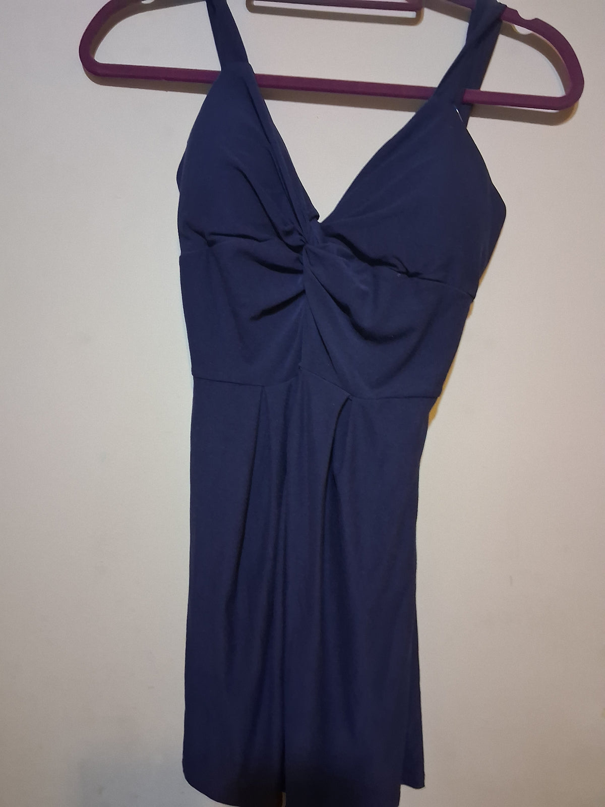 Navy Twist-Front Sleeveless Dress displayed on a hanger, showcasing its stylish twist-front detail and V-neckline.